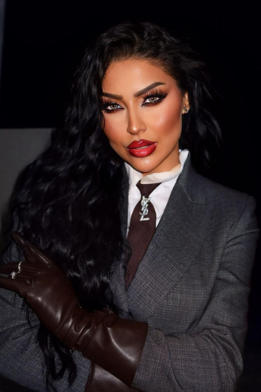 Woman in a gray suit with a fur stole and leather gloves against a dark background